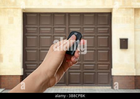 Woman using remote to control electric gate outdoors, closeup Stock Photo