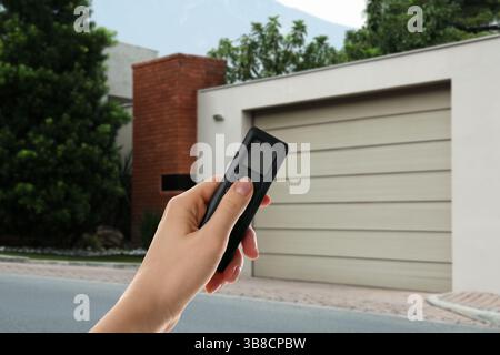 Woman using remote to control garage door outdoors, closeup Stock Photo
