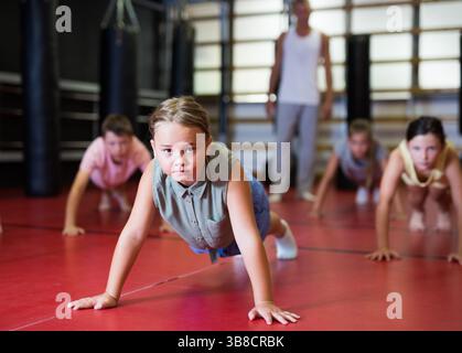Children doing bench press exercises in gym Stock Photo