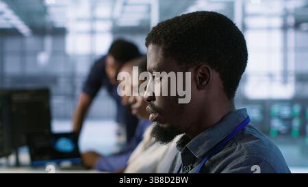 System administrators in data center implementing AI systems. Server farm specialists using artificial intelligence to identify hardware failures impacting operations, camera A handheld camera shot Stock Photo