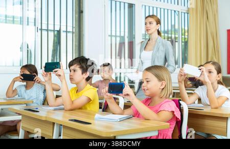 Pupils using mobile phones during lesson in school Stock Photo