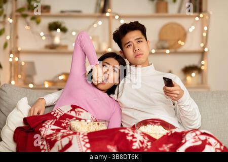 Bored Chinese Couple Watching TV Yawning Celebrating Christmas At Home Stock Photo