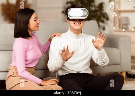 Asian Couple Using Virtual Reality Headset Having Fun At Home Stock Photo