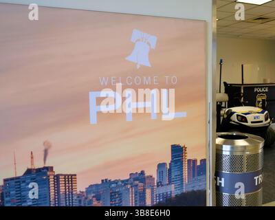 Welcome to PHL sign with Liberty Bell icon and city skyline at the Philadelphia International Airport in Philadelphia, Pennsylvania; police booth. Stock Photo