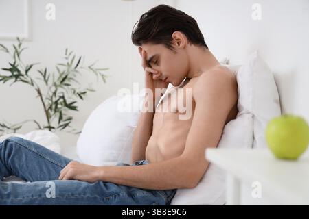 Young man with anorexia refusing from food in bedroom Stock Photo