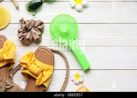 Female summer accessories and mini fan on white wooden background Stock Photo
