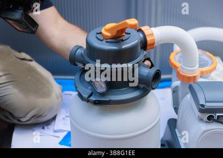 Plumber is installing pool filter system, checking connections gauges in backyard environment. Stock Photo