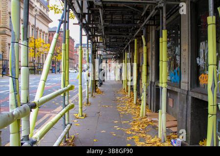 Construction site on empty street with no pedestrians and workers on site. Trash and leaves on the empty street. Stock Photo