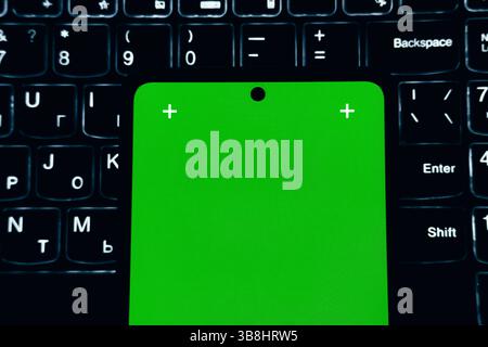 Green screen smartphone on the led-lighted laptop keyboard. Stock Photo