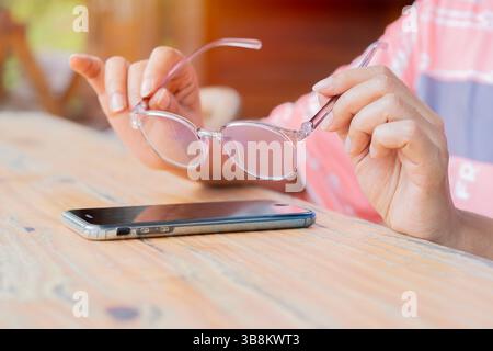 Hands of hispanic woman holding glasses and ready to wear before enjoy social on smart phone. Selective focus. Stock Photo