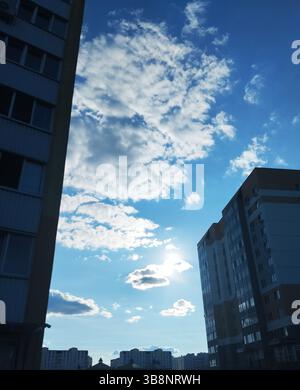 Blue sky with white clouds on a sunny day between houses. Cityscape. Stock Photo