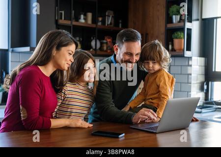 Happy family with kid having fun using laptop together, parents and child laughing relaxing at home with computer watching funny internet video, makin Stock Photo