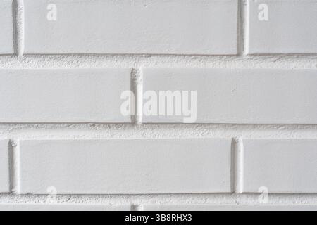 Painted white brick wall providing a minimalistic, textured backdrop. Light catches the rough surface, highlighting the clean lines and geometry Stock Photo