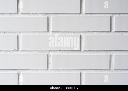 Simple white brick wall providing a clean and minimalist background. Texture and pattern offer a versatile backdrop for graphic design Stock Photo