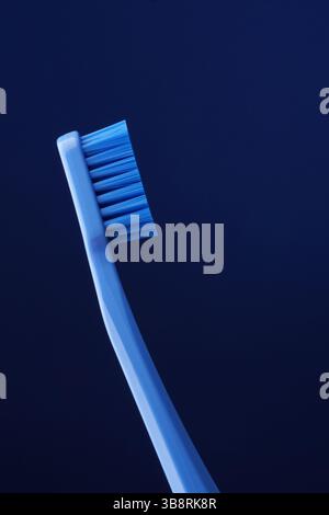 Blue plastic toothbrush on a dark blue background. Oral hygiene. Dentistry. Stock Photo