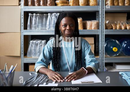 Smiling Woman Sitting at Desk in Office Setting Stock Photo