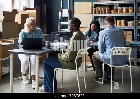 Diverse Team Having Meeting in Modern Warehouse Setting Stock Photo