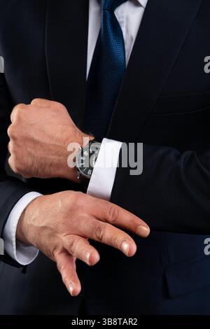 Close-up of a businessman in suit adjusting his white shirt sleeve, showcasing a wristwatch. Concept of elegance, detail, and professionalism. Stock Photo