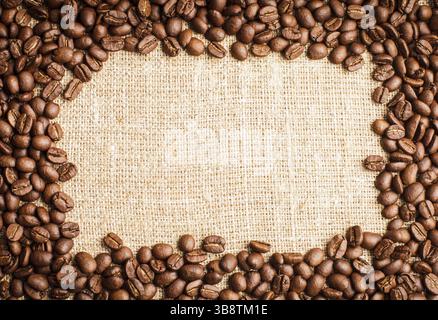 Spilled coffee beans frame over burlap textile Stock Photo