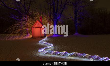 Lightpainting with colourful, glowing light effects in front of a chapel in the snow, surrounded by sparks, St Anna Chapel, Mindelheim, Unterallgaeu d Stock Photo