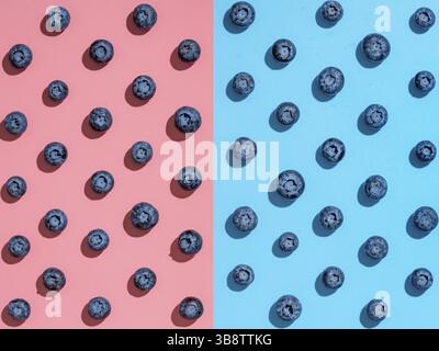 Blueberry pattern. Minimalistic concept. Top view or flat lay. Blueberries staggered on two colors background. Pink and blue minimalistic background Stock Photo