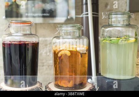 Glass jars filled with lemon, orange and apple juice on wooden stumps Stock Photo