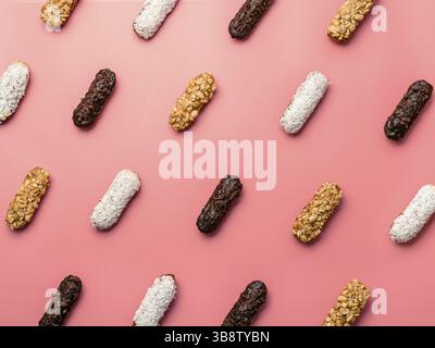Pattern of different homemade eclairs on pink background. Top view of delicious healthy profitroles with different decor - chocolate, peanut and sherd Stock Photo