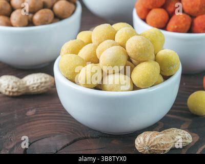 Peanut snack for beer, wine, party bar. Salted peanuts in yellow cheese glaze on brown wooden table. Copy space Stock Photo