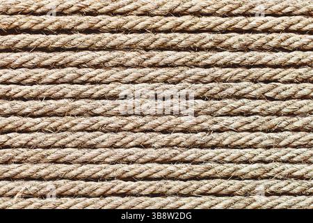Brown twisted rope pattern background. Natural fiber cords in parallel lines. Textured string surface for nautical or craft themes.. Stock Photo