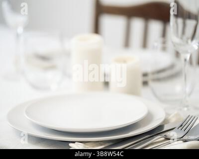 Beautiful table setting in white colors. Empty white plates. Set table for romantic dinner for two at home Stock Photo