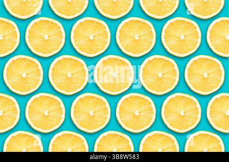 Vibrant yellow lemon slices isolated on blue background. Fruit sections design texture. Vitamin diet pattern. Flat design fruit section. Stock Photo