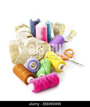Sewing items: multicoloured threads, pins, meter and scissors on white Stock Photo