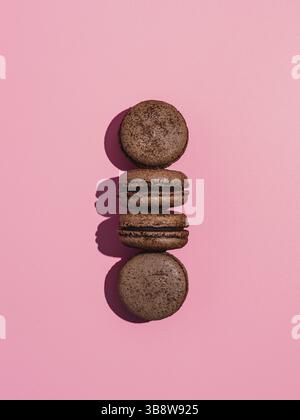 Chocolate macarons with copy space. Row of perfect french macarons or macaroons on pink background. Top view or flat lay. Hard light Stock Photo