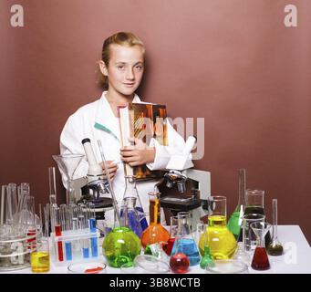 Schoolgirl standing near blackboard in the laboratory classes in chemistry. Focus on the microscope Stock Photo