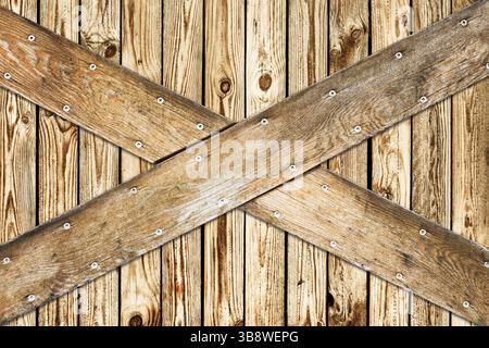 Crossed wooden planks with metal nails on rustic timber wall. Wood background for construction carpentry barrier texture renovation and rural design. Stock Photo