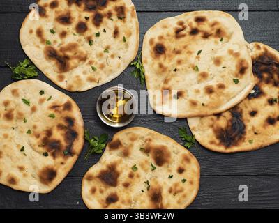 Fresh naan bread on dark wooden background with copy space. Several perfect naan flatbreads top view or flat lay Stock Photo