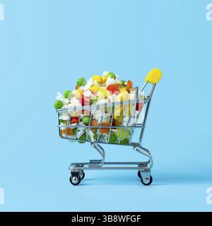 Frozen vegetables assorted in toy shopping cart on blue background. Full of assorted frozen vegetables food shop trolley. Square crop Stock Photo