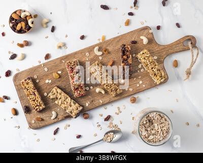 Granola bar with copy space. Set of different granola bars on cutting board over white marble table. Shallow DOF. Top view or flat lay Stock Photo