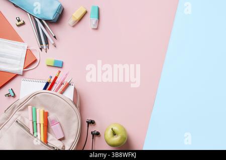 Creative student desk with colorful modern school supplies on blue and pink duotone background. Top view. Flat lay. Copy space. Back to school concept Stock Photo