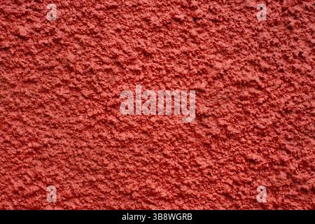 Red rough wall texture. Stucco plaster background. Painted surface closeup with grunge detail. Solid building material with abstract structure. Stock Photo