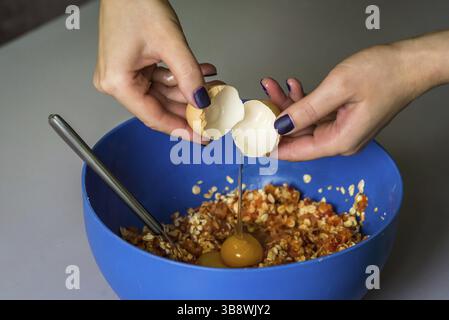 Hand poured down a raw egg with shell in blue bowl Stock Photo