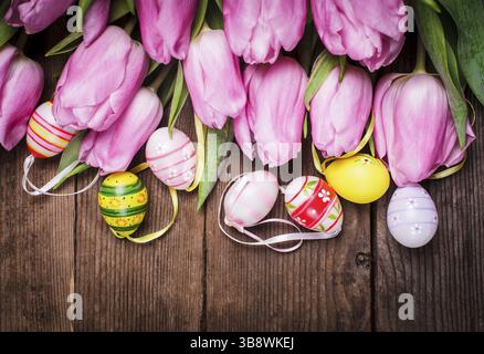Tulips and eggs border over wooden backdrop. Easter decorations Stock Photo