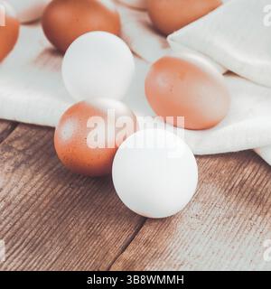 Beige and white chicken eggs on textile tablecloth over rustic wooden table Stock Photo