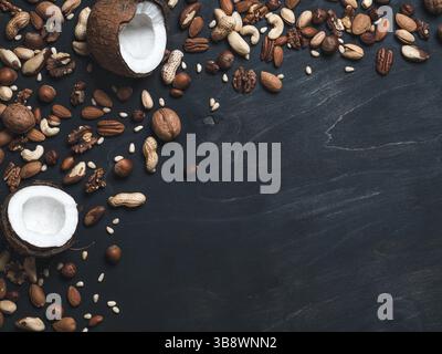 Background of mixed nuts - coconut, hazelnuts, walnuts, almonds, pecan, pistachio, brazil nut, pine nuts, peanut - on dark background. Copy space. Iso Stock Photo