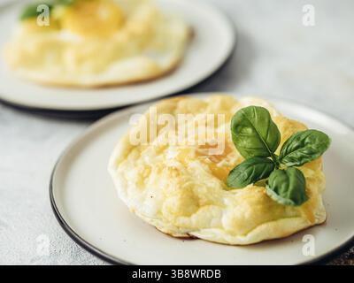 Fluffy Cloud Eggs. Trendy food - oven bake scrambled eggs with whipped egg white and whole yolk on plate Stock Photo