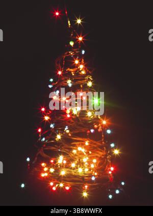 Blurred colorful lights as a silhouette of Christmas tree on black Stock Photo