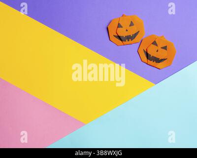 Halloween concept. Paper origami pumpkin on colorful background. Simple idea for halloween - easy made paper pumpkins on multicolor background. Copy s Stock Photo