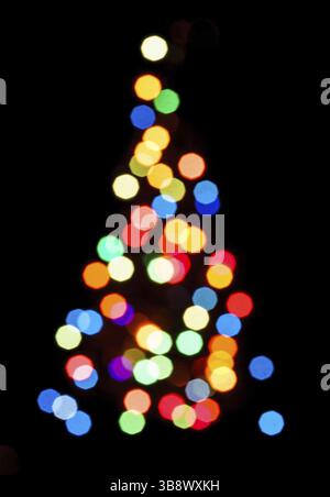 Blurred colorful lights as a silhouette of Christmas tree on black Stock Photo
