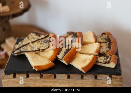 Delicious slices of a freshly baked sweet cake with plum jam and crumble topping, served on a black slate plate Stock Photo