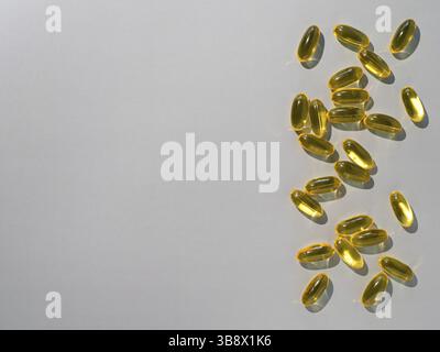 Vitamin D3, Omega or Evening Primula Oil gel capsules on neutral gray background. Top view or flat lay yellow liquid capsules with nutritional supplem Stock Photo
